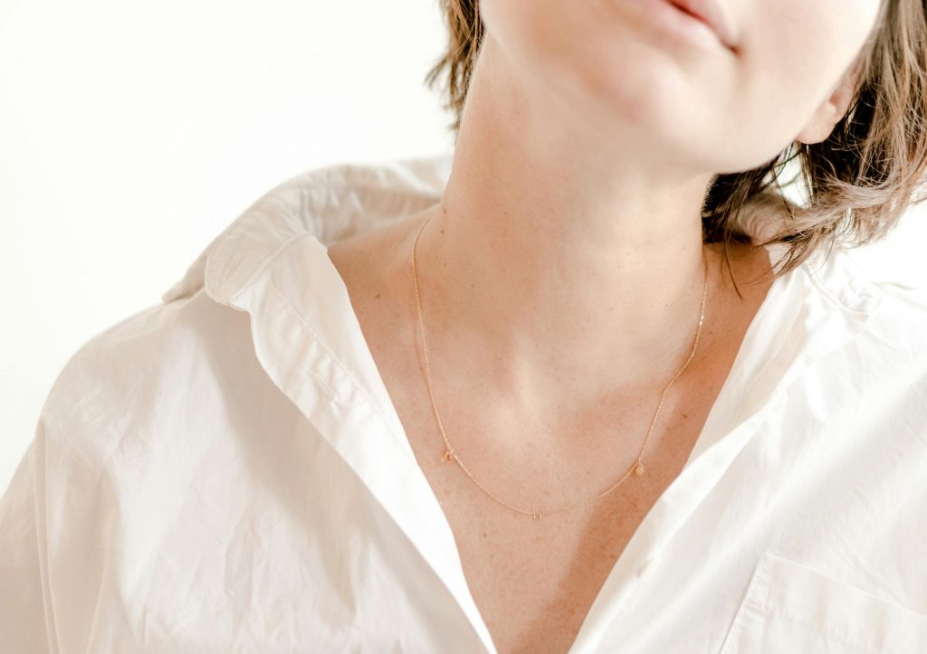 Close-up of a woman wearing a delicate gold necklace with a serene expression.